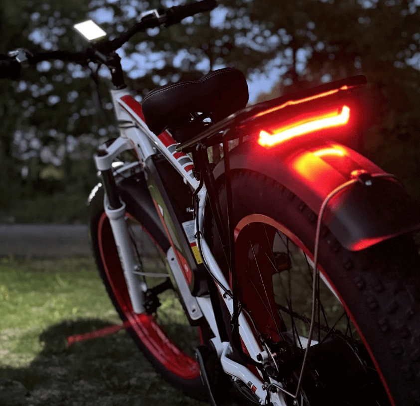 1000W SENADA ARCHON PLUS fat tire electric bike with rear red light illuminated at night, featuring a durable rear rack for cargo.